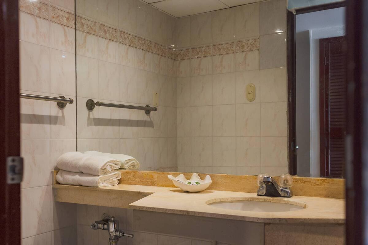 Une salle de bain équipée d’un lavabo, d’un miroir, d’un porte-serviettes et d’un bol décoratif.