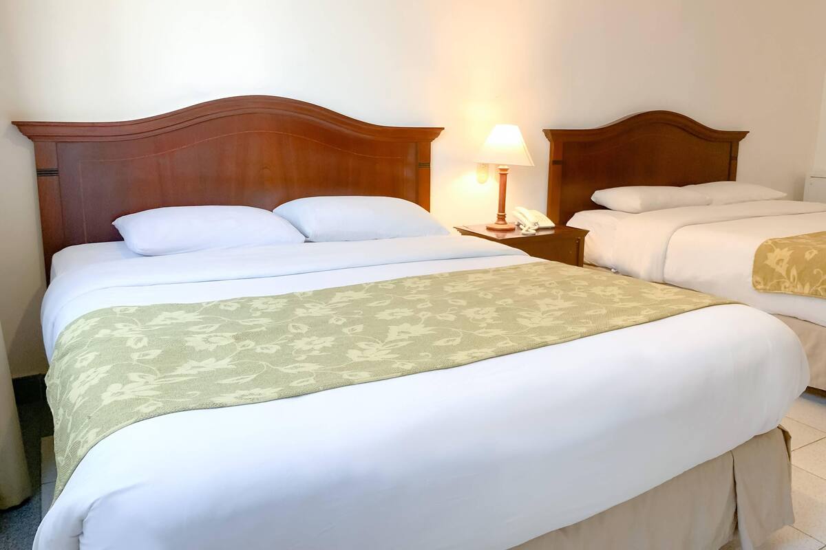 Une chambre d’hôtel avec un grand lit, une table de chevet avec une lampe et un téléphone.
