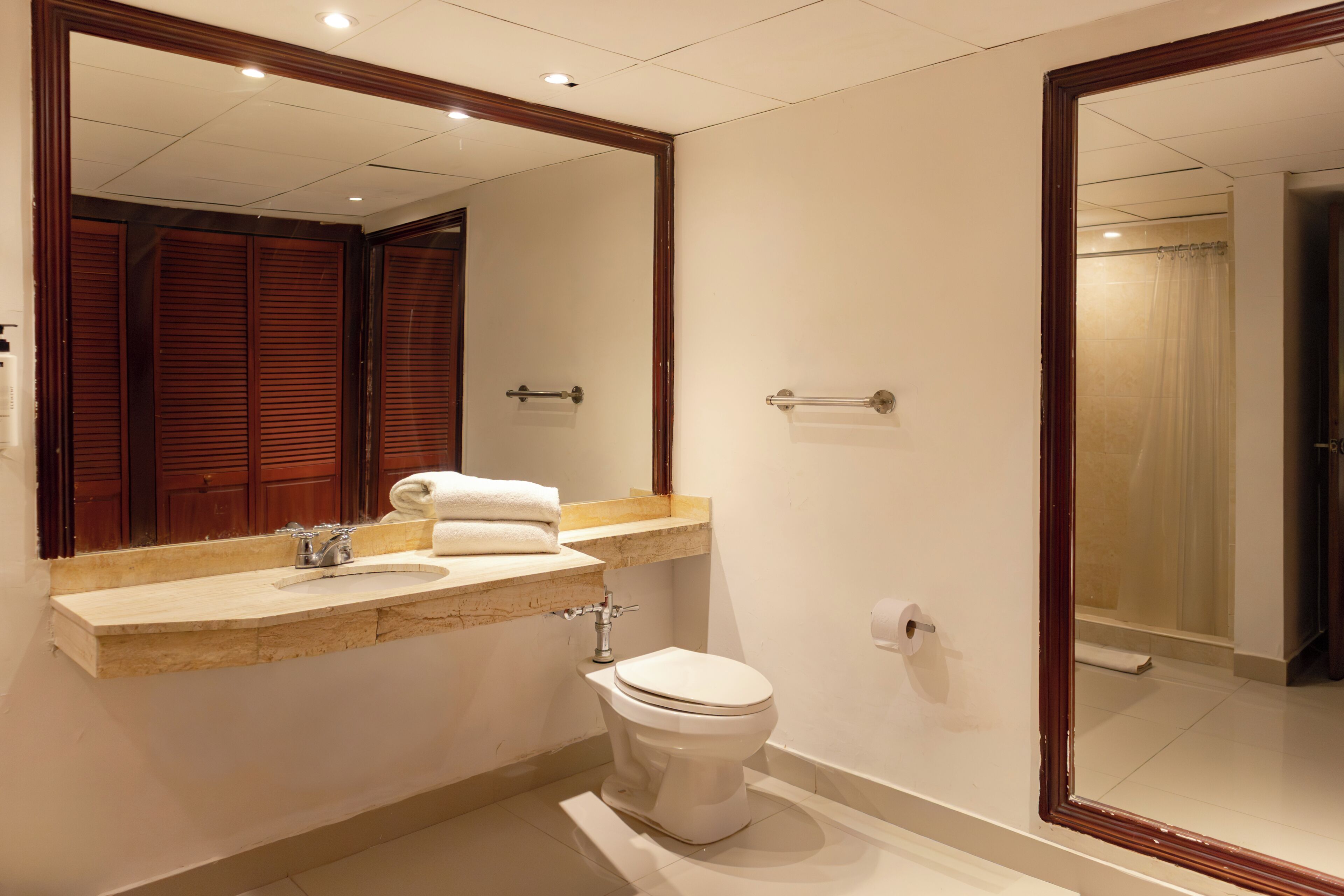Un baño con lavamanos, inodoro y espejo.