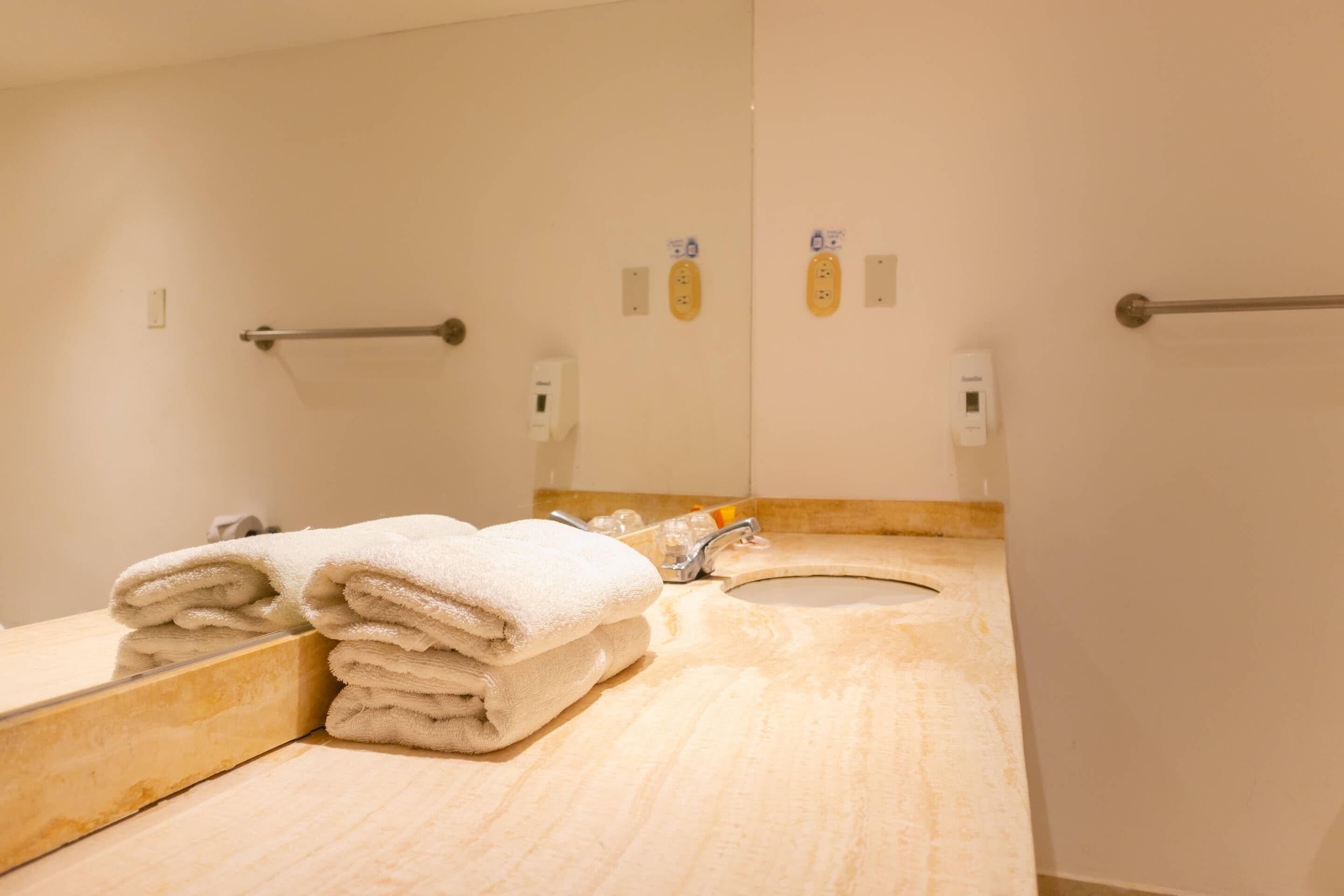 A bathroom with a sink, mirror, towel rack, and hand dryer.