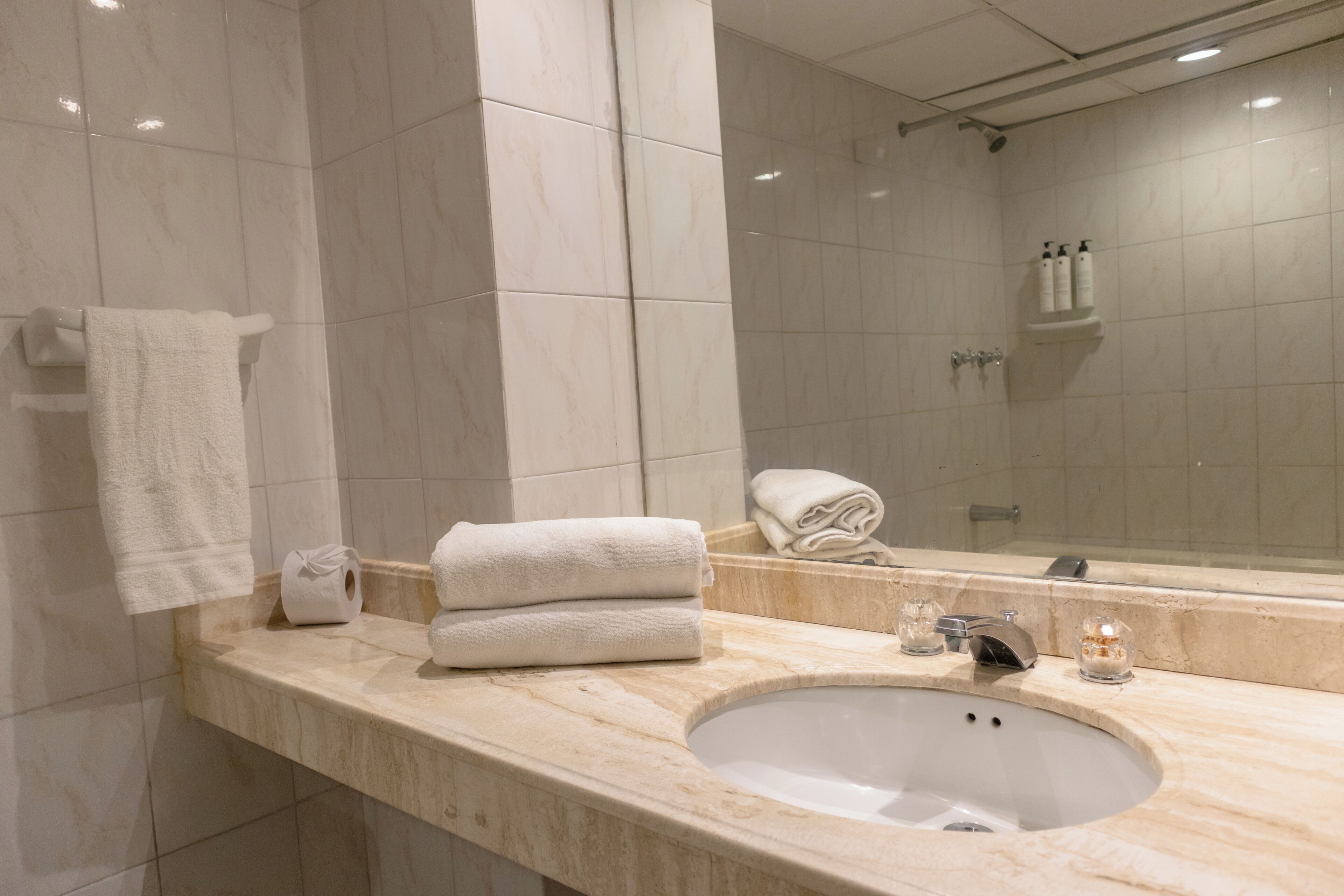 A bathroom with a marble sink, a mirror, and two towels on the counter.