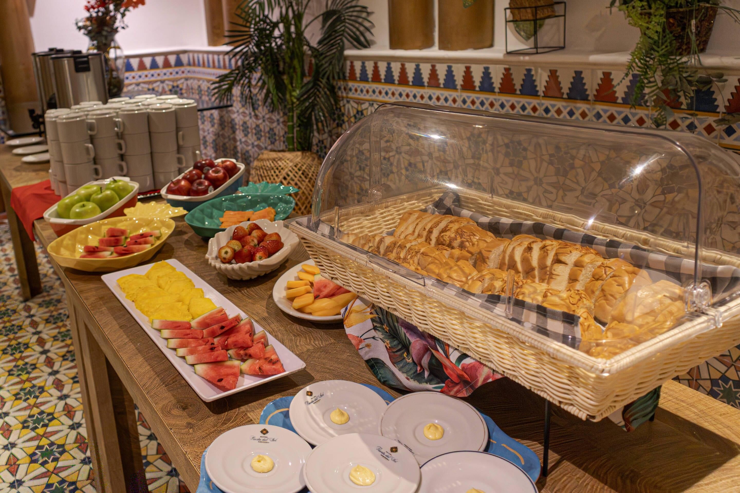 A buffet with various food items, including fruits, pastries, and bread.