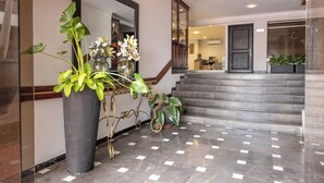 A lobby with a large potted plant, a mirror, and a staircase leading to another area. - Hotel Faranda Express Puerta Del Sol Barranquilla, A Member of Radisson Individuals (Barranquilla)