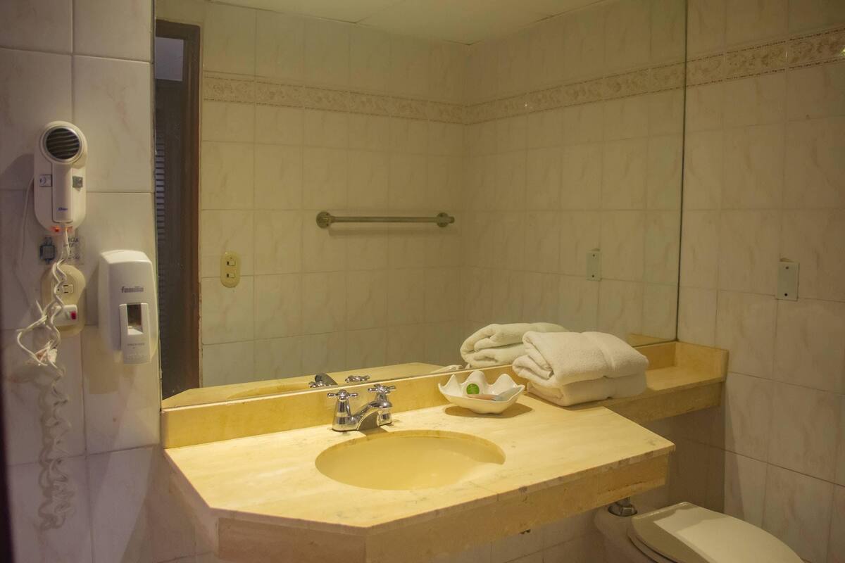 Une salle de bain équipée d’un lavabo, d’un miroir, d’un porte-serviettes et d’un sèche-cheveux.