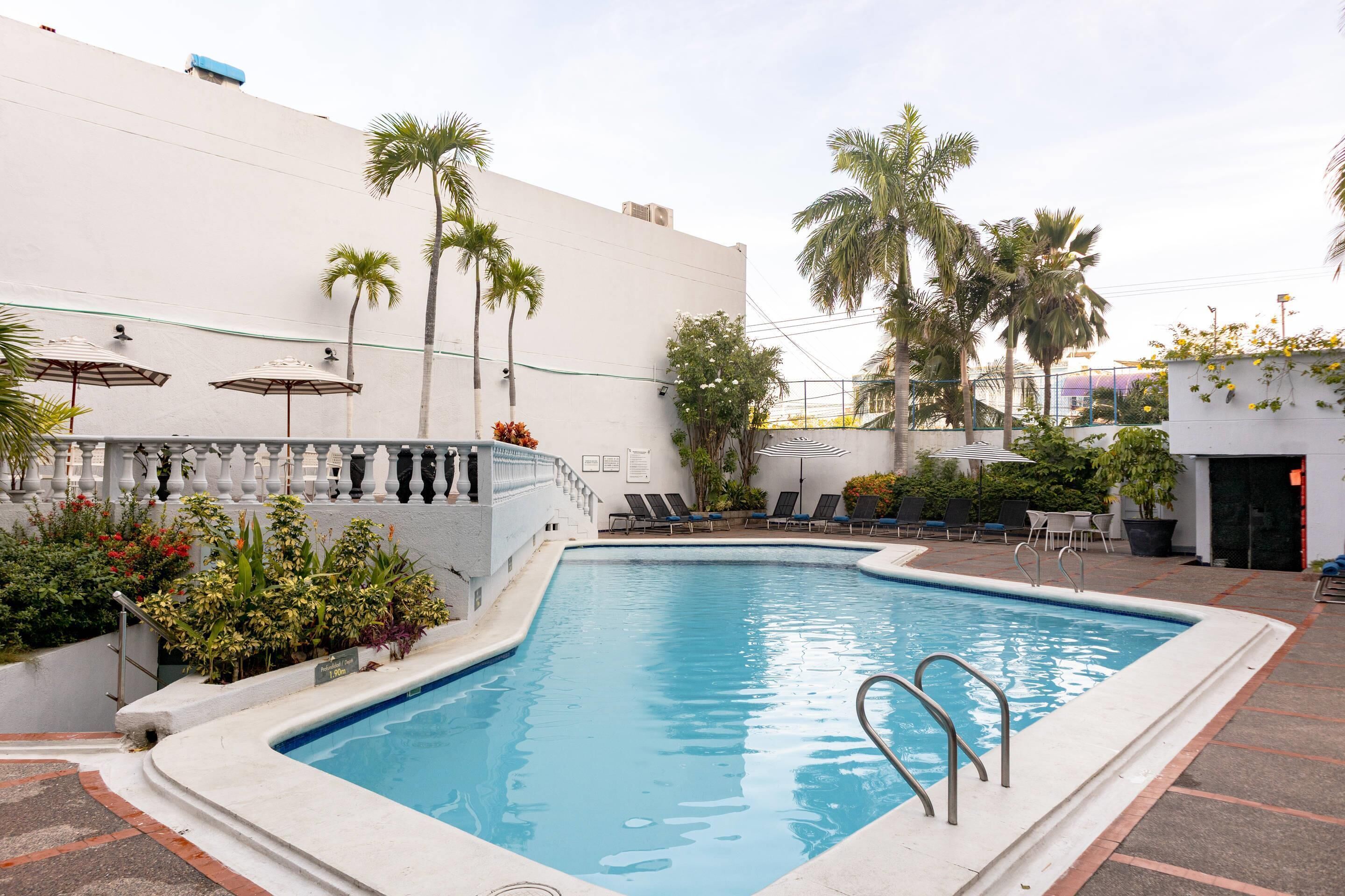 Una piscina con sillas de descanso y palmeras.