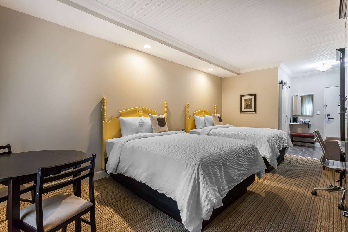 A hotel room with two beds, a desk, and a chair.