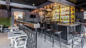 Eine Bar mit Theke, Hockstühlen und einer Auswahl an Flaschen.