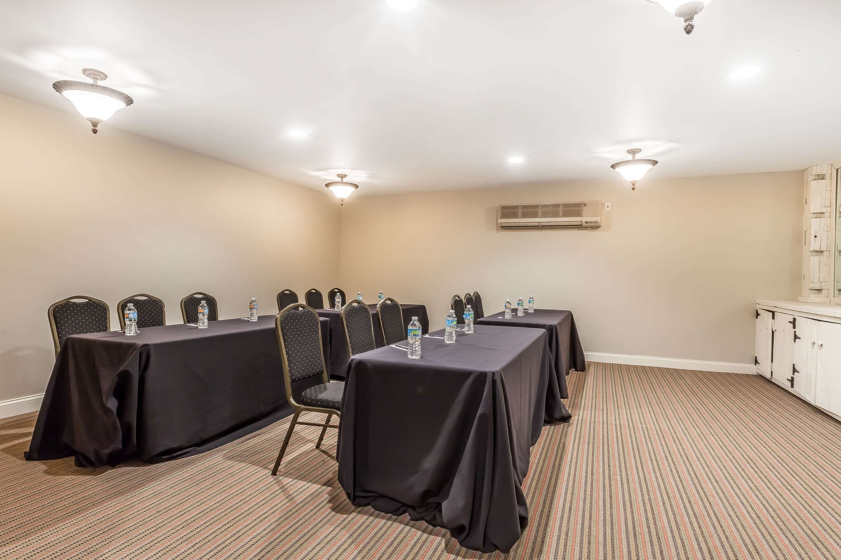 Un salón de conferencias con mesas, sillas e iluminación en el techo.