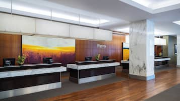 A reception area with a marble reception desk, a large painting on the wall, and a wooden panel design.