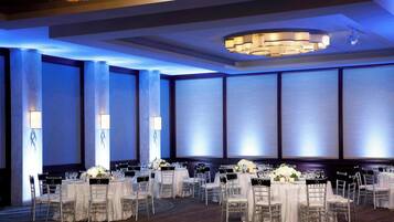 Un salón de banquetes con mesas redondas, sillas y candelabros.