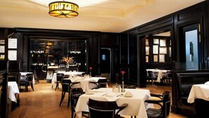 A restaurant with multiple tables and chairs, a wine rack in the background, and a chandelier. - The Westin Michigan Avenue Chicago (Chicago)