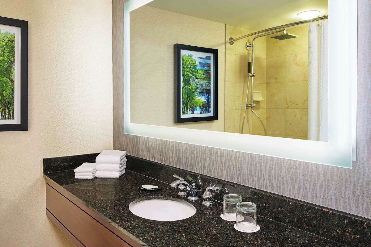 A modern bathroom with a large mirror, a sink, and a shower.