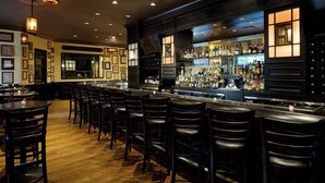 A bar area with multiple stools and a bar counter stocked with bottles. - The Westin Michigan Avenue Chicago (Chicago)