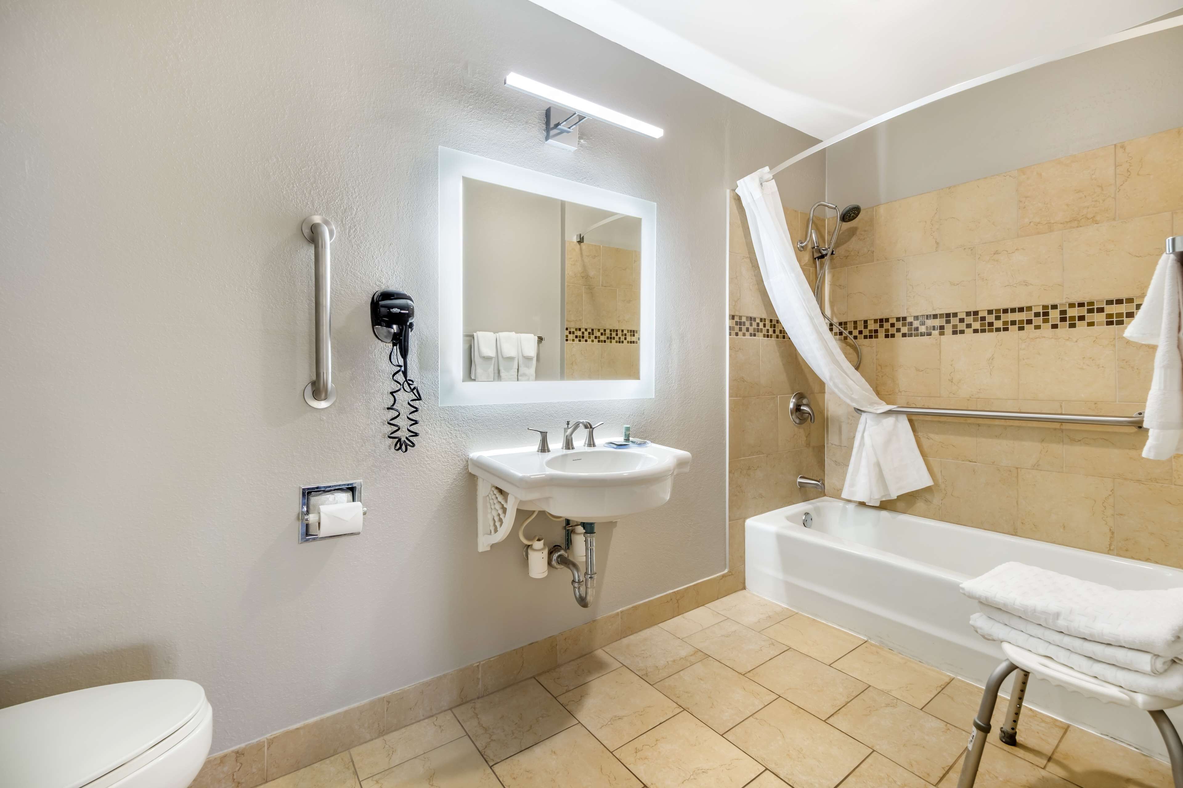 A modern bathroom with a sink, mirror, toilet, and bathtub.