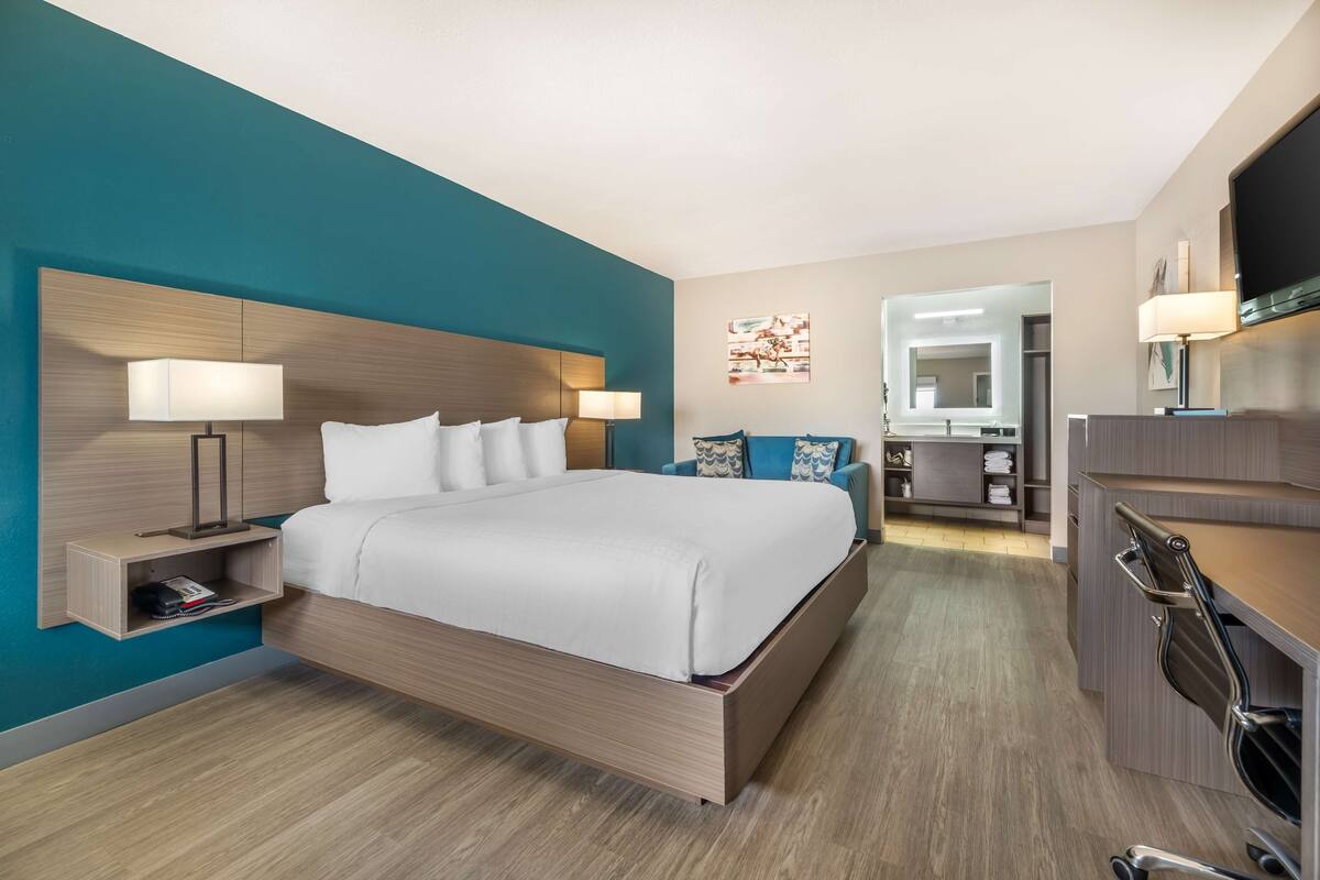A modern hotel room with a large bed, bedside tables, a desk, and a chair.