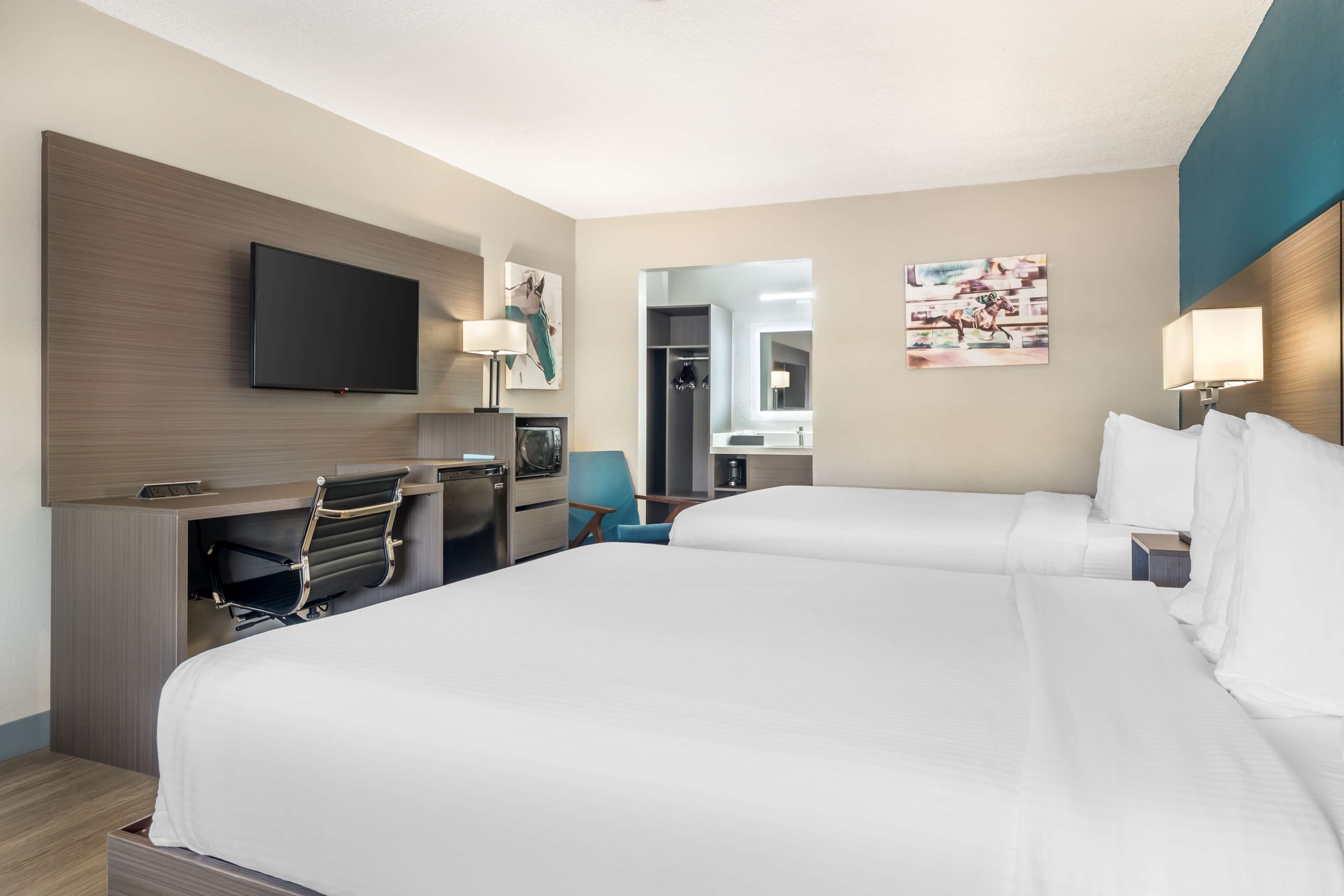 Une chambre d’hôtel avec deux lits, un bureau, une chaise, une télévision et un miroir.