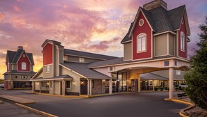 A hotel with a central building and two smaller structures, featuring a covered entrance and a parking area.