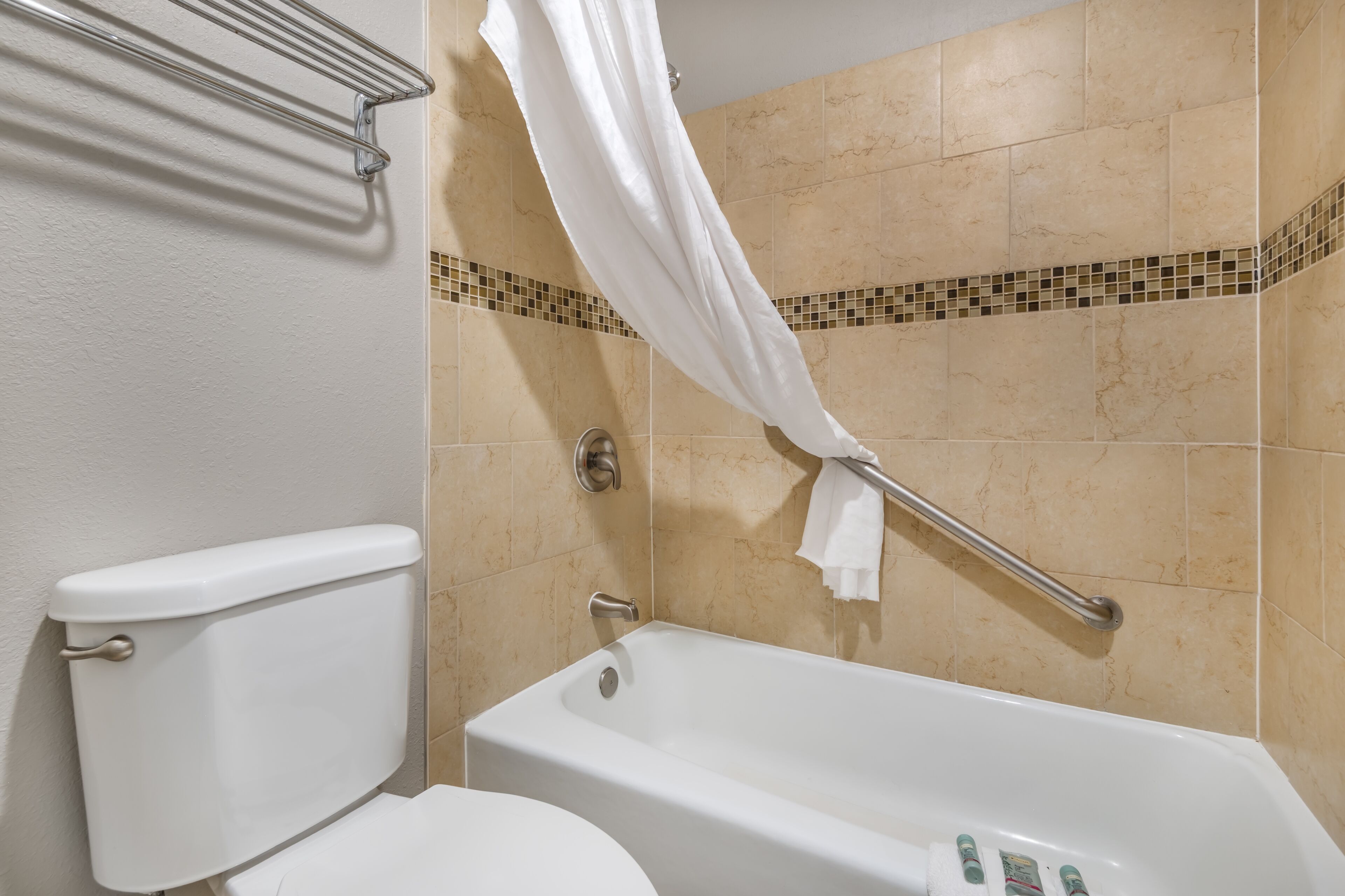 A bathroom with a bathtub, toilet, and a shower curtain.