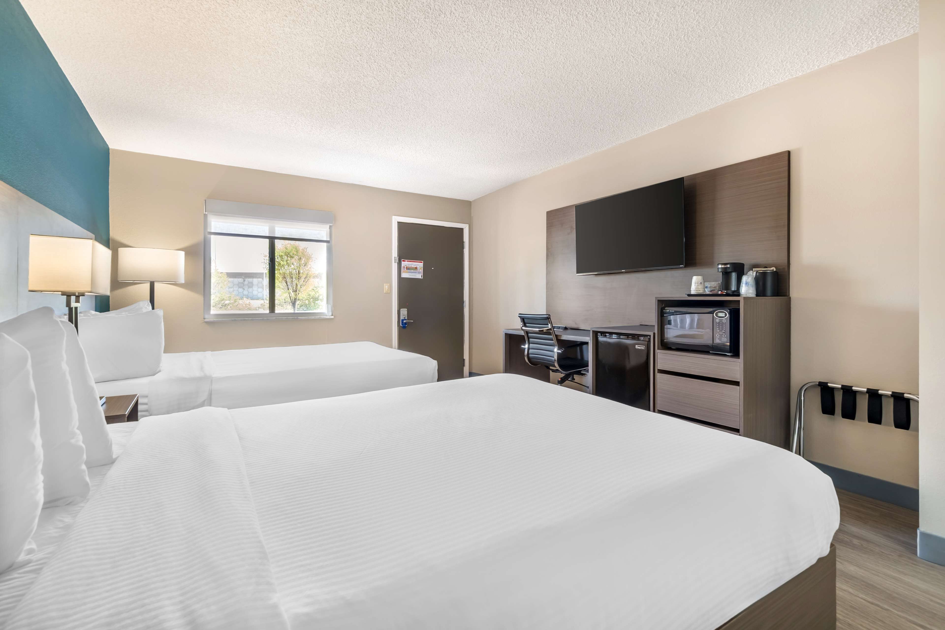 Une chambre d’hôtel avec deux lits, une télévision, un four à micro-ondes et une petite kitchenette.