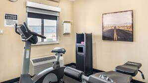 A fitness center with exercise equipment, a treadmill, a stationary bike, and a motivational poster on the wall.