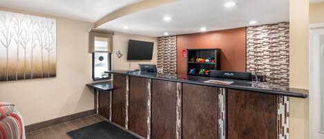 A reception area with a wooden reception desk, a flat-screen TV, and a wall-mounted sign.