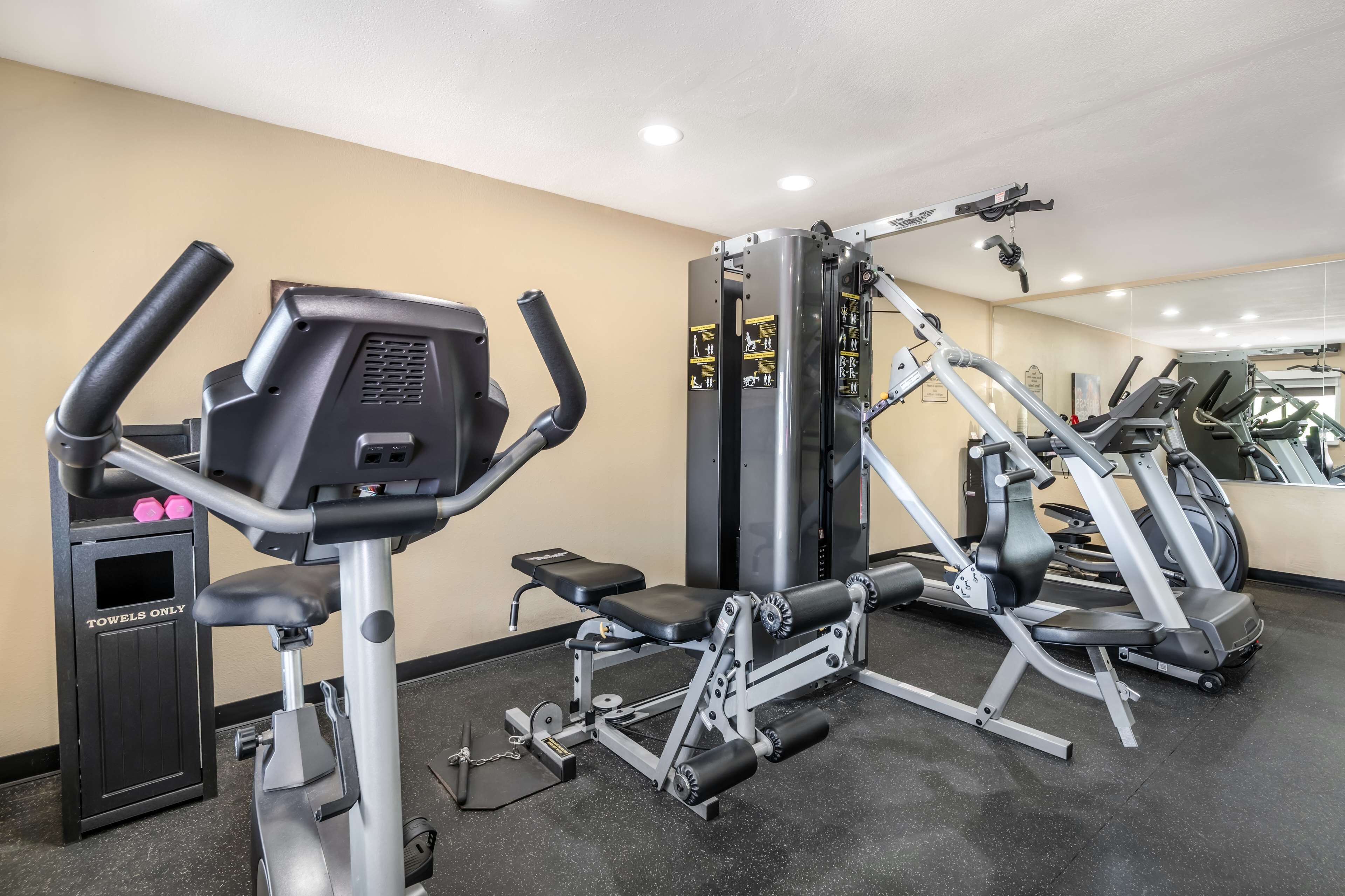 Ett gym med konditionsmaskiner, styrketräningsmaskiner och en träningsbänk.