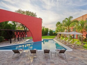 A swimming pool with lounge chairs and a red arch structure. - Fiesta Inn Express Aguascalientes (Aguascalientes)