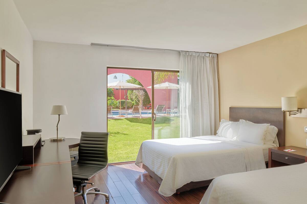 Quarto de hotel com uma cama, uma mesa, uma cadeira e uma televisão.