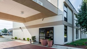 Une entrée d’immeuble dotée d’un espace abrité, d’un panneau indiquant une hauteur libre de 12 pieds 6 pouces, et de plantes en pot.