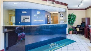 Un espace d’accueil d’hôtel avec un comptoir bleu, une horloge et un bureau de réception.