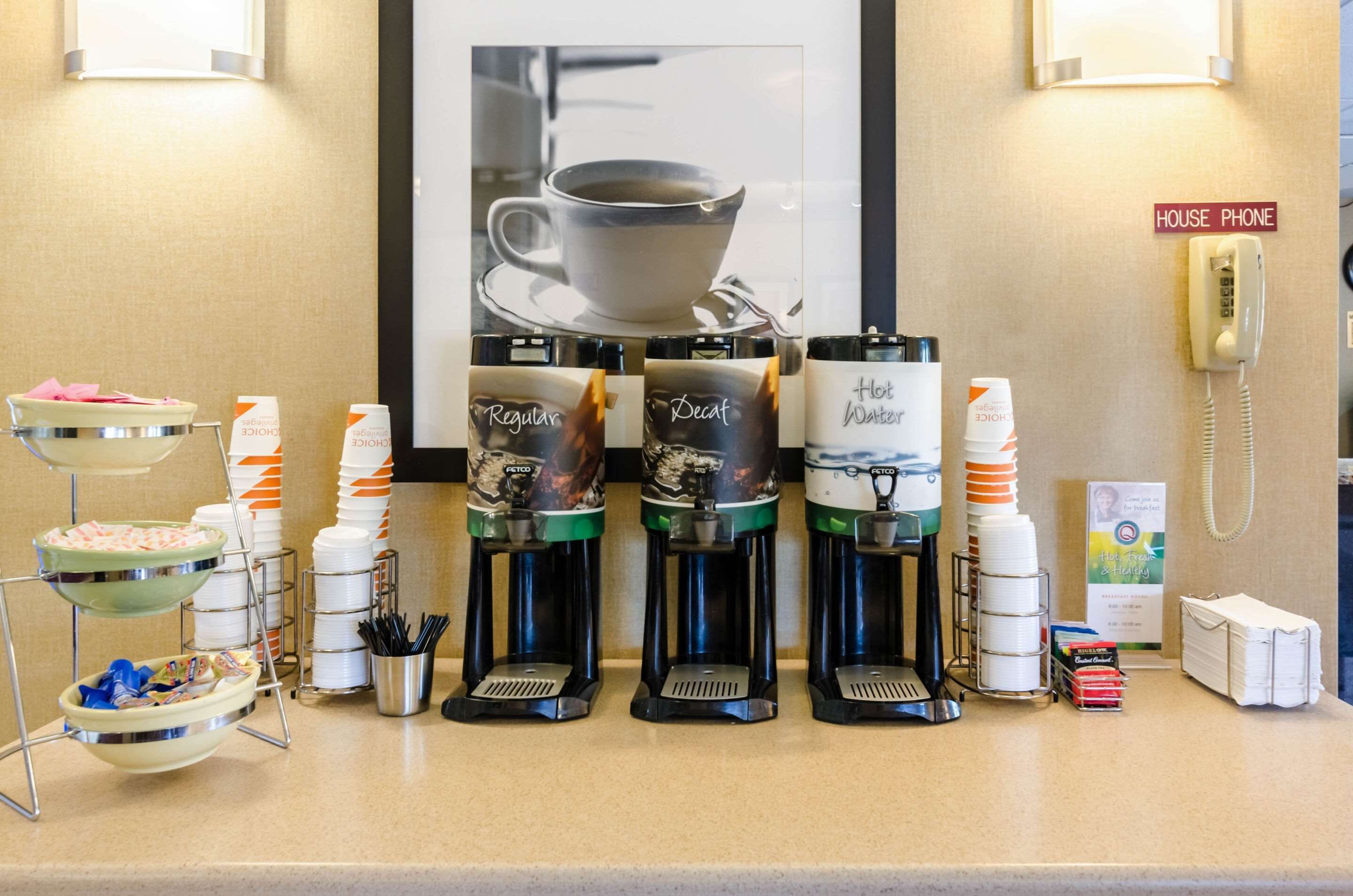 A coffee station with multiple coffee makers, a bowl of snacks, and a sign indicating a house phone.