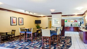 Un hall d’hôtel comprenant un espace repas, un bar et un téléviseur fixé au mur.