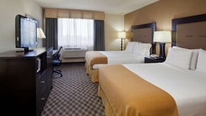 A hotel room with two beds, a desk with a television, and a window with curtains.