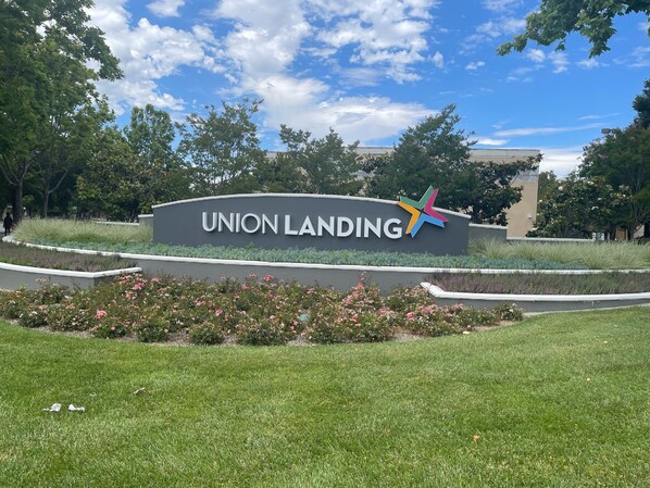 Señal de Union Landing con un logotipo de estrella colorido, rodeada de césped cuidado y plantas florecientes.