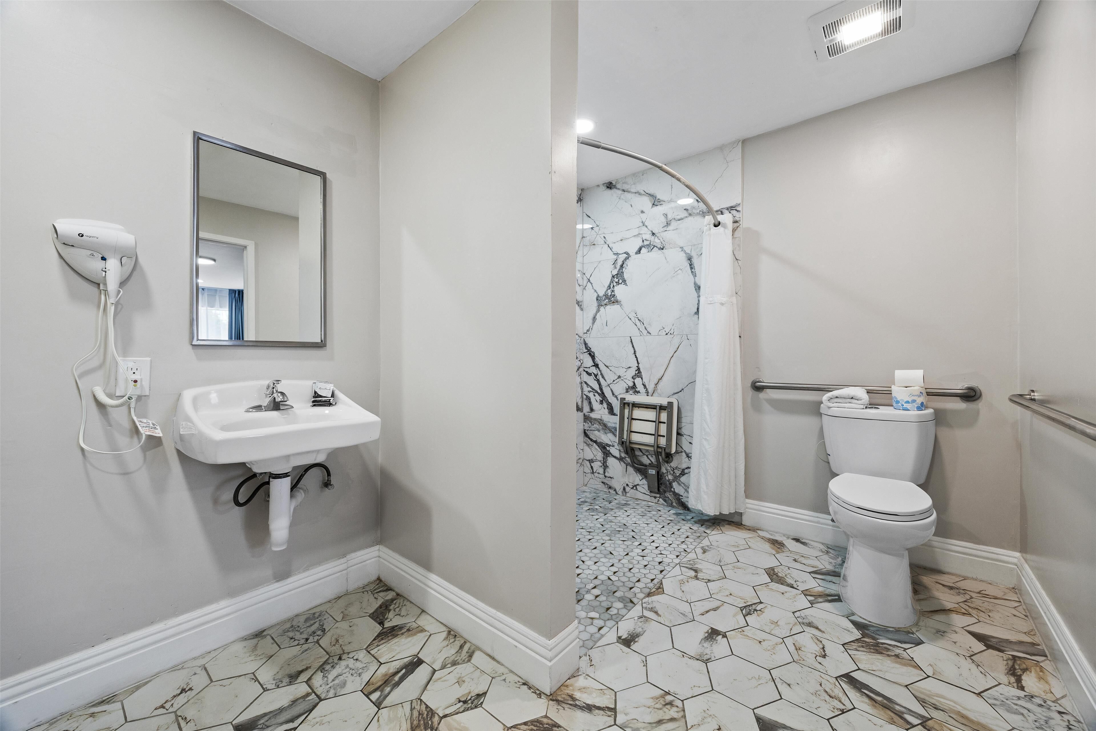 A bathroom with a white sink, mirror, and toilet.