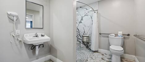 A bathroom with a white sink, mirror, and toilet.