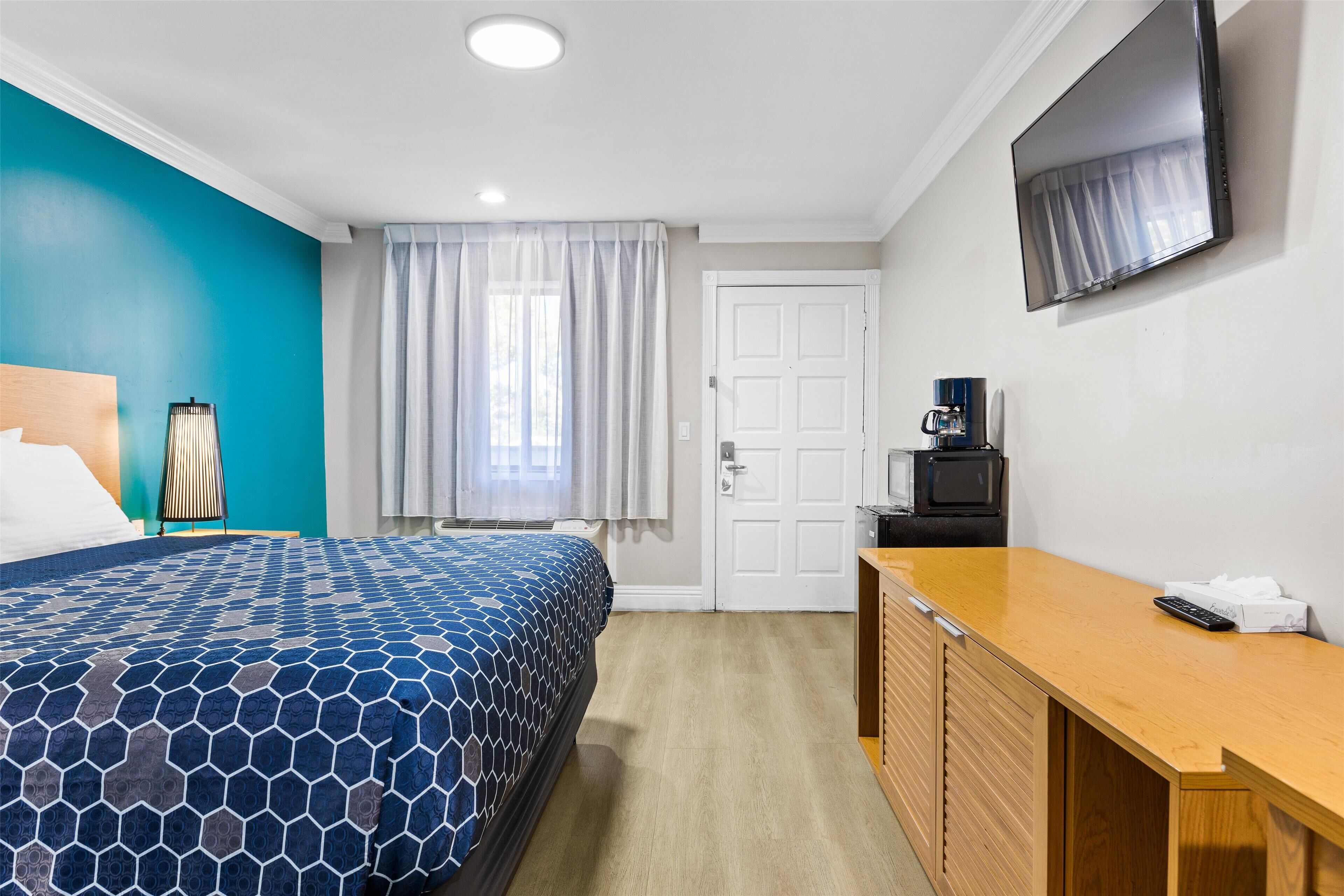 A hotel room with a bed, a desk, a television, and a coffee maker.