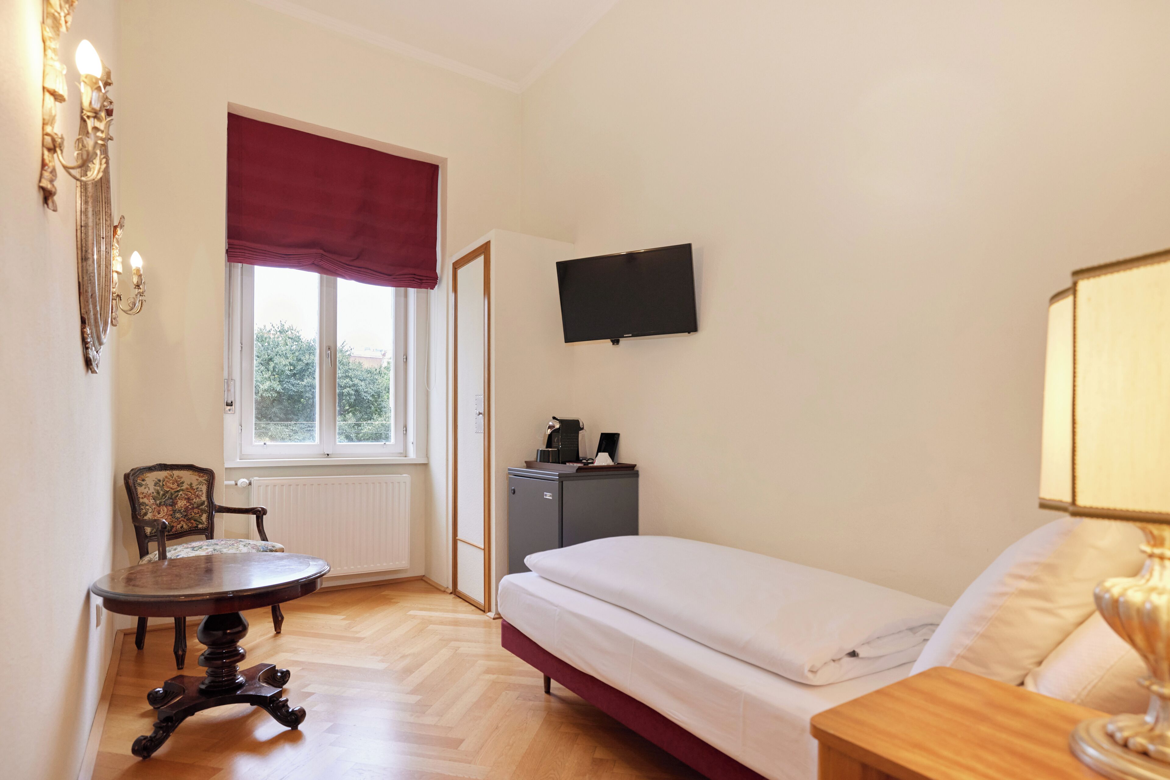 Une chambre à coucher comprenant un lit, un bureau, une chaise, un téléviseur et un radiateur.