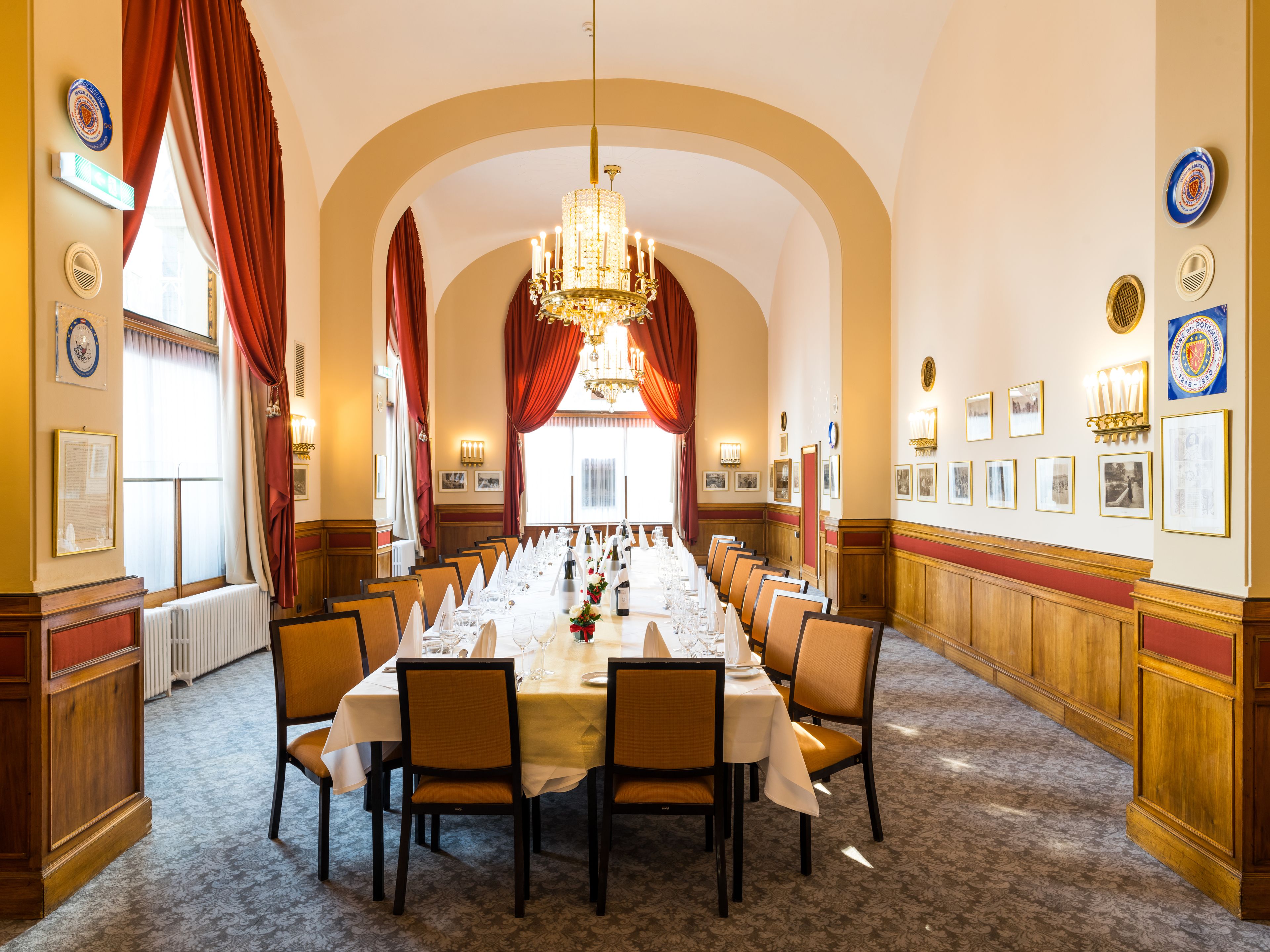 A formal dining room with a long table set for a banquet, arched ceiling, and chandeliers.