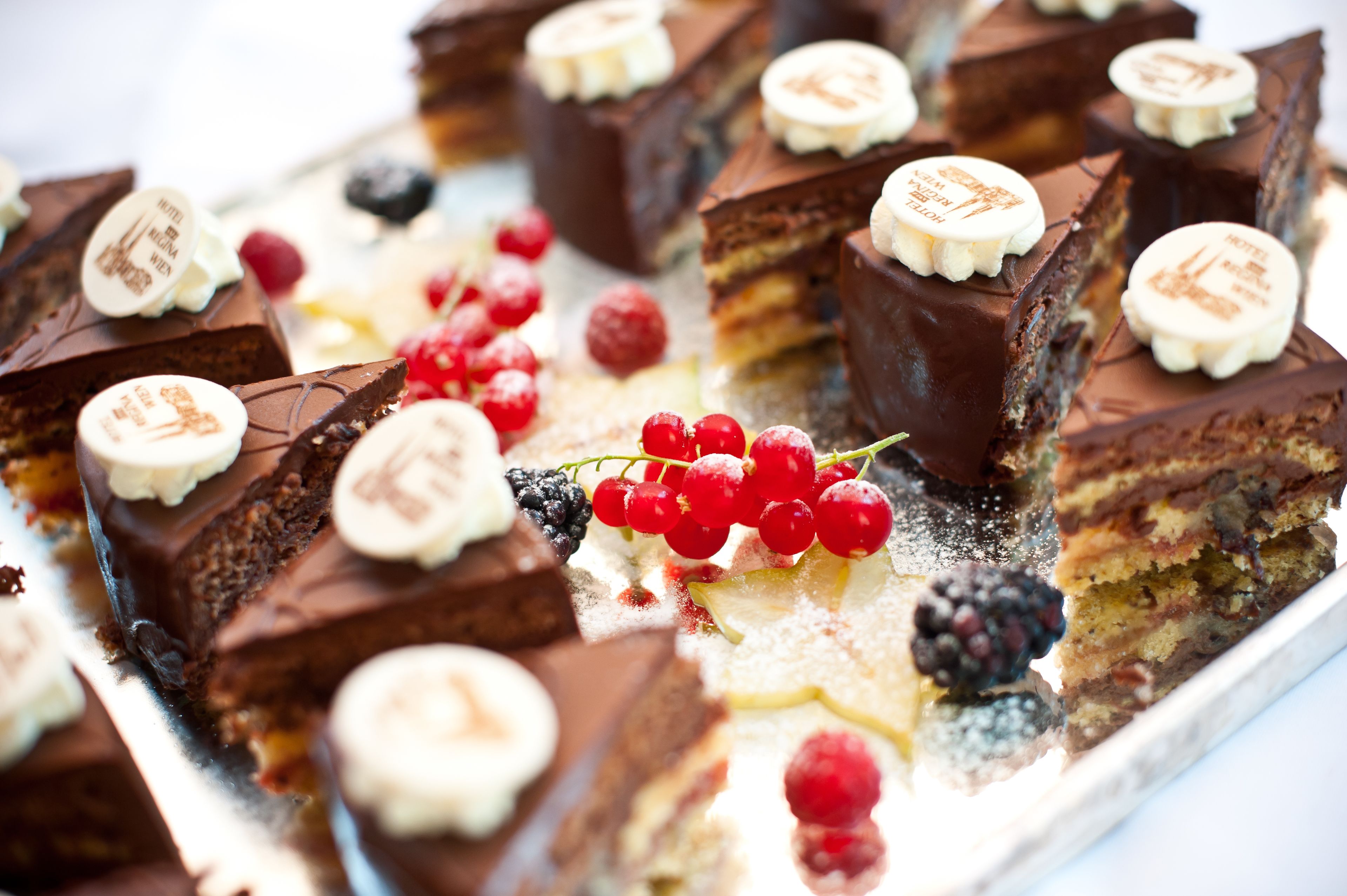 A tray of assorted desserts, including chocolate-covered squares and slices with various toppings like berries and nuts.