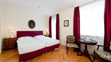 A hotel room with a large bed, two bedside tables, a round table, and two chairs.