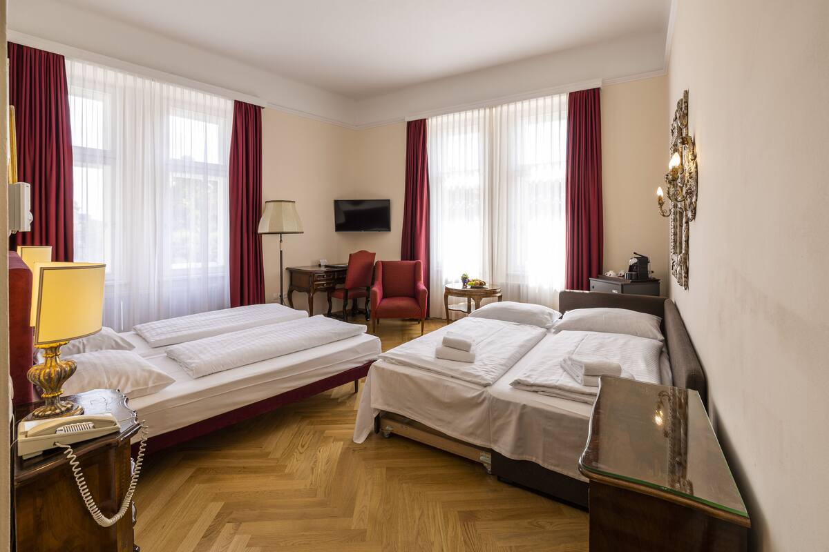 Een hotelkamer met twee bedden, een bureau met lamp, een stoel, een televisie en een nachtkastje met lamp.