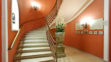 A staircase with a curved handrail, a potted plant, and framed pictures on the wall.