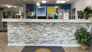 A reception desk with a stone facade, a 'Days Inn' mat, and a 'Check in Time' sign. - Days Inn by Wyndham Oglesby/ Starved Rock (Oglesby)