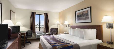 A hotel room with a bed, desk, chair, television, and a window with curtains.