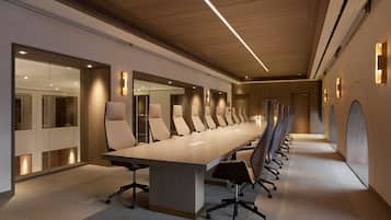 A modern conference room with a long table and chairs, wooden ceiling, and glass partitions.
