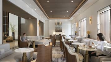 A modern hotel lobby with seating areas, tables, and a central decorative piece.