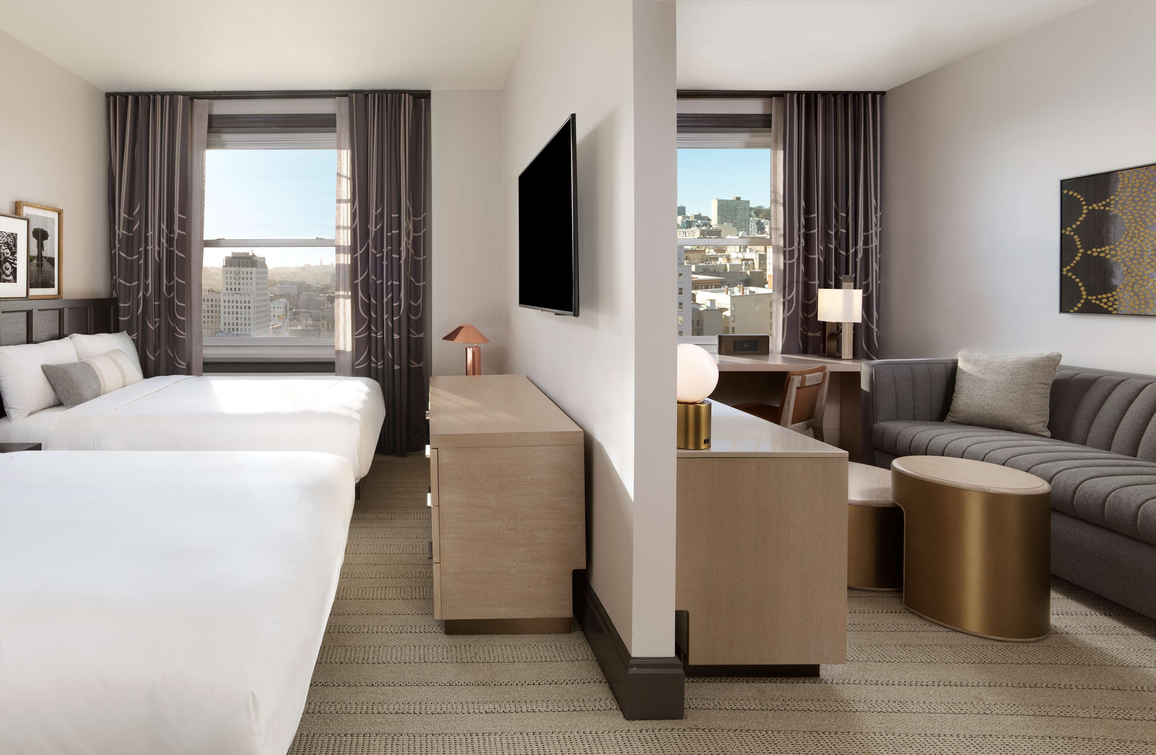 Una habitación de hotel moderna con una cama grande, un sofá, un escritorio con lámpara y un televisor.