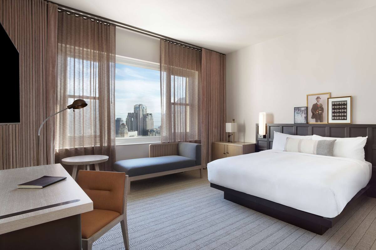 Une chambre d’hôtel comprenant un lit, un bureau, une chaise, une petite table, un canapé et une vue sur la ville.