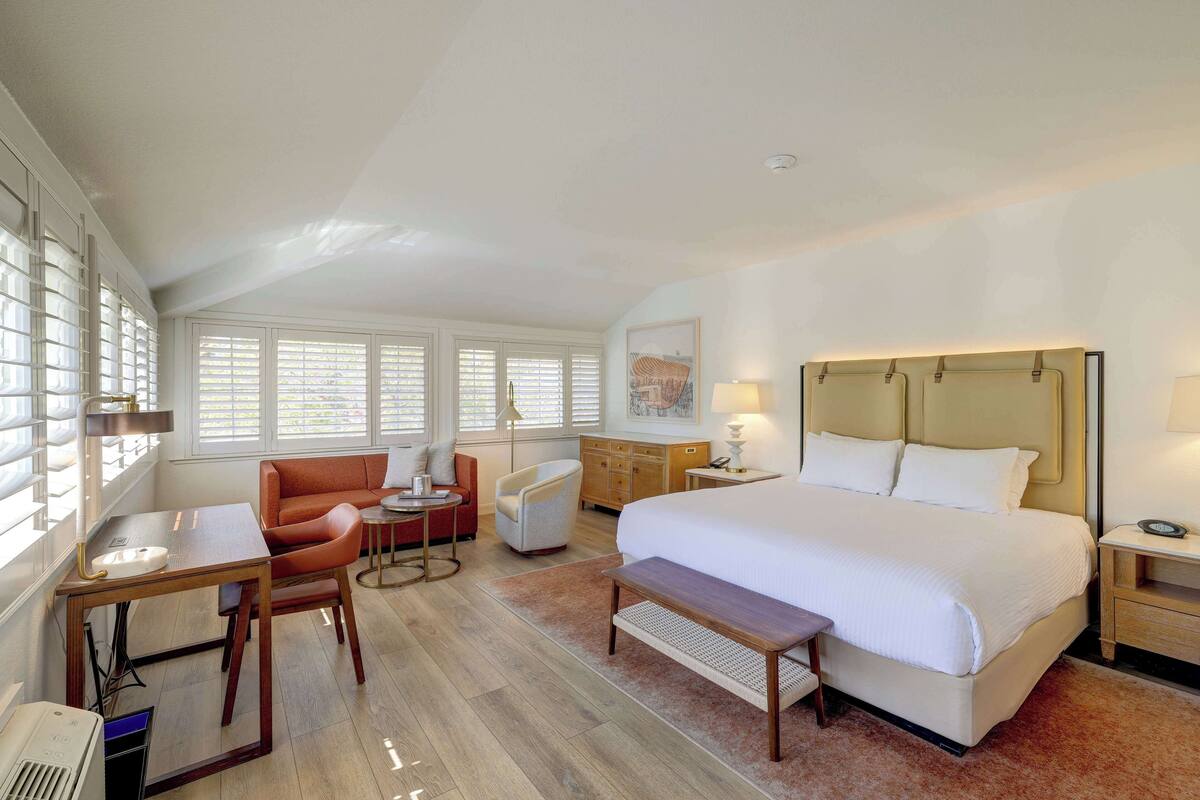 Una habitación de hotel con una cama grande, un escritorio, una silla, un sofá y una mesita.